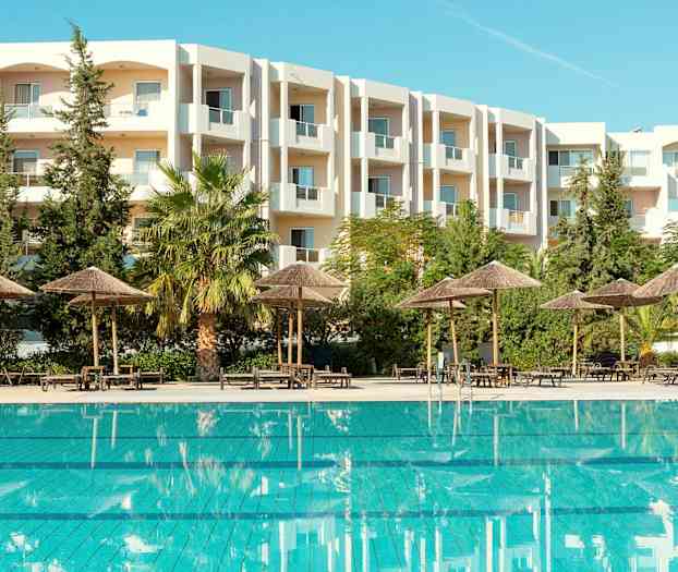 Utomhuspool med parasoller och en vit byggnad i bakgrunden. (AI-genererad text)