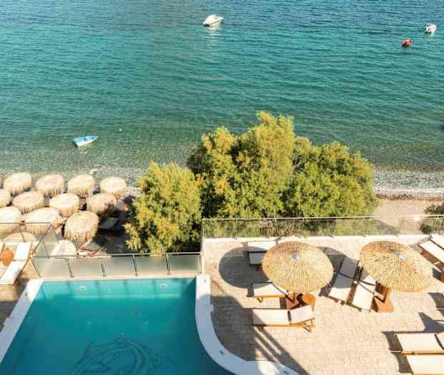 Poolområde med solstolar och parasoller nära stranden och havet. (AI-genererad text)