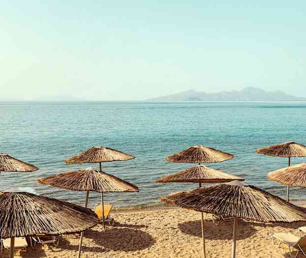 Strand med parasoller av halm vid havet. (AI-genererad text)