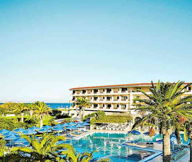Hotellbyggnad med flera våningar omgiven av palmer och en stor pool. (AI-genererad text)