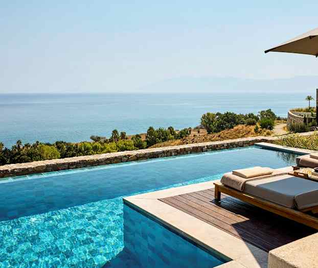 En infinitypool med utsikt över havet och ett grönskande landskap. (AI-genererad text)