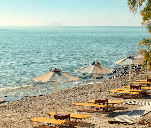 Solstolar och parasoller på en sandstrand med utsikt över havet. (AI-genererad text)