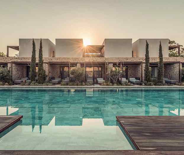 Bild av en modern villa med en pool framför, omgiven av växtlighet och träd, med solens strålar synliga bakom byggnaden. (AI-genererad text)