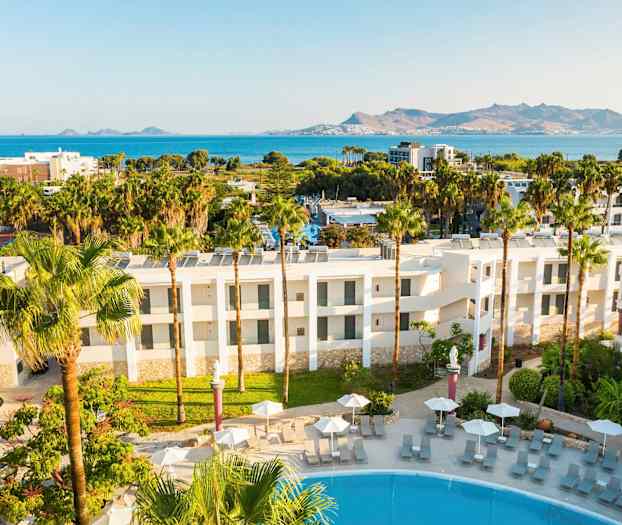 Hotellets utsida med poolområde och utsikt över havet och bergen. (AI-genererad text)