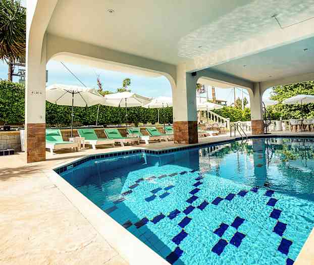 Utomhuspool under tak med solstolar och parasoller runtom. (AI-genererad text)