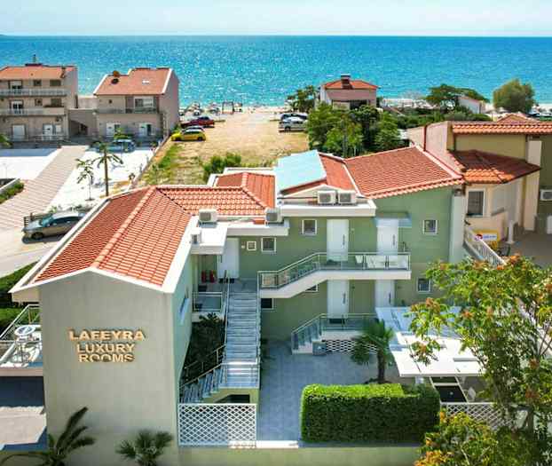 Vy över ett hotell med röda tak och klarblått hav i bakgrunden. (AI-genererad text)