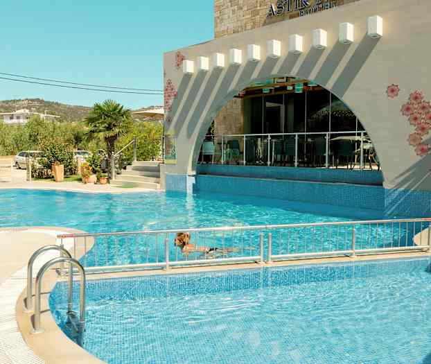 En utomhuspool framför ett hotell med dekorativ fasad. (AI-genererad text)