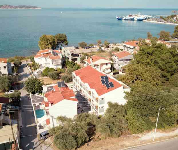 Flygvy över en kuststad med hus och byggnader, havet i bakgrunden. (AI-genererad text)