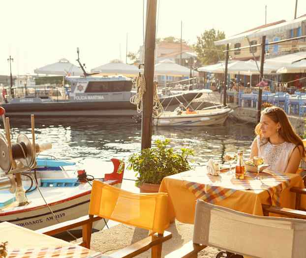 En utomhus restaurang med utsikt över en marina med småbåtar och en polisbåt. (AI-genererad text)