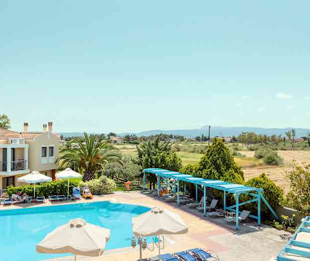 En pool med solstolar och parasoller omgiven av träd och en byggnad. (AI-genererad text)