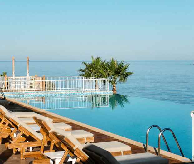 En infinitypool med solstolar intill och med utsikt över havet. (AI-genererad text)