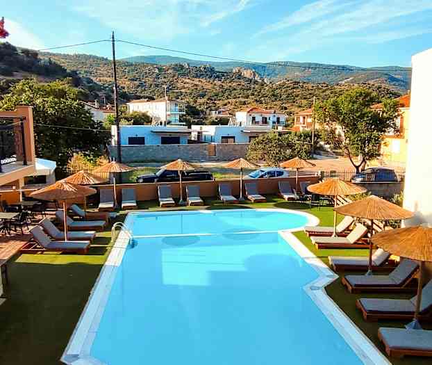 Utomhuspool med solstolar och parasoller, omgiven av grönska och byggnader. (AI-genererad text)