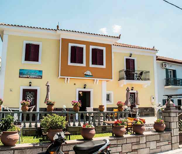 Flerfärgad byggnad med balkonger och blomkrukor framför. (AI-genererad text)