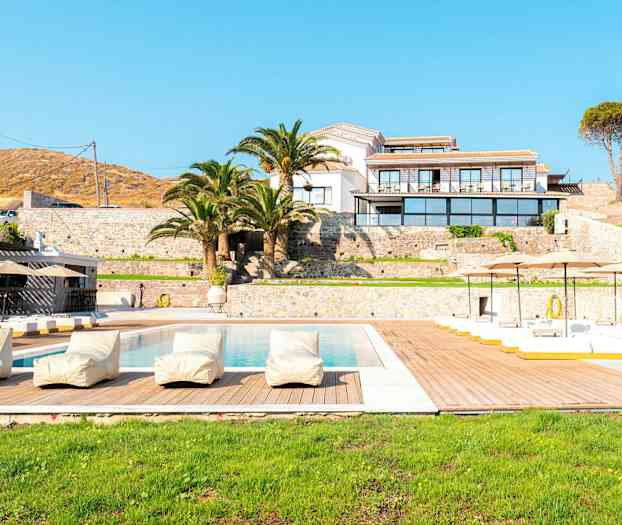 En lyxig resort med pool, solstolar och palmer framför en byggnad. (AI-genererad text)