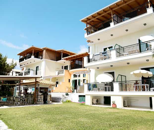 Flera byggnader med balkonger och utemöbler, omgivna av grönskande gräsmattor. (AI-genererad text)