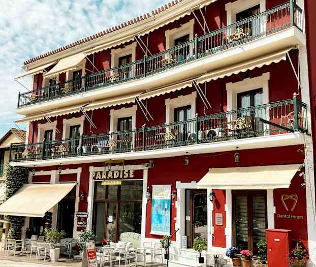 Röd byggnad med tre våningar, balkonger och skyltar inklusive 'Paradise'. (AI-genererad text)
