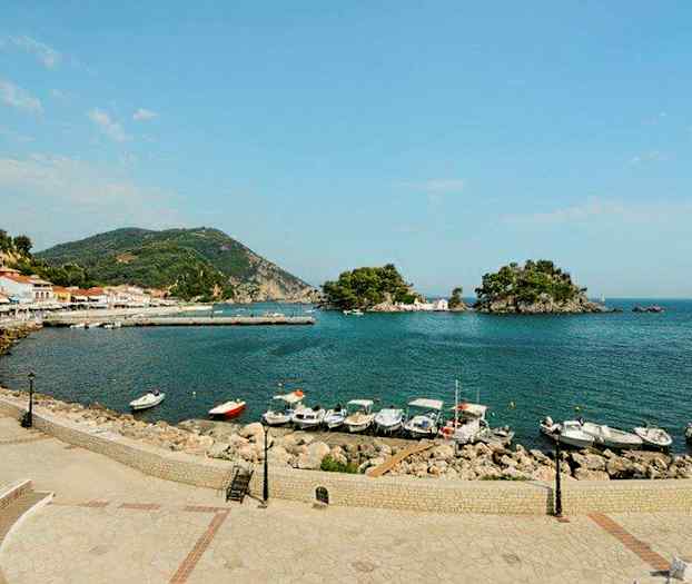 Vy över en hamn med flera båtar, omgivna av berg och små öar. (AI-genererad text)