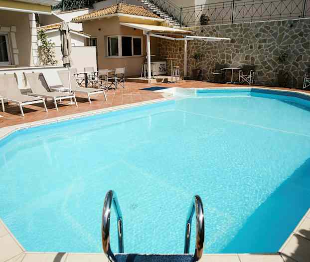 Utomhuspool med solsängar och parasoller vid sidan. (AI-genererad text)