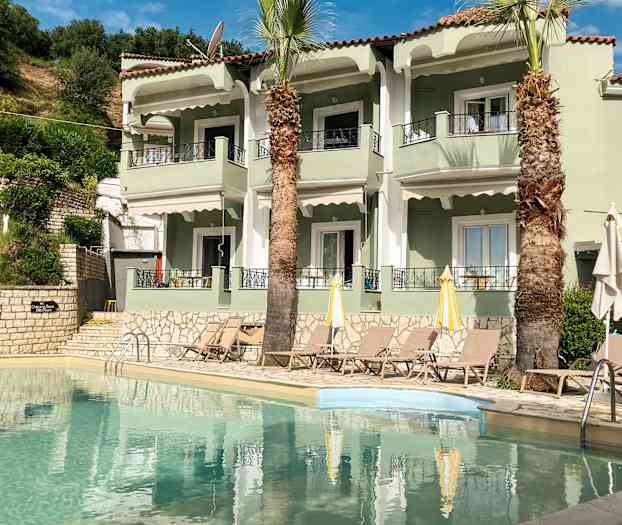 Lägenhetskomplex med pool och solstolar framför. (AI-genererad text)