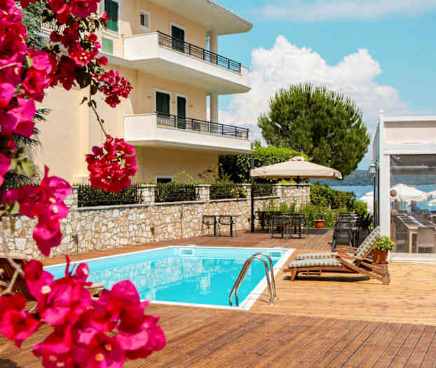 Bild av en byggnad med balkonger, en pool och möbler på en solterrass med blommor i förgrunden. (AI-genererad text)