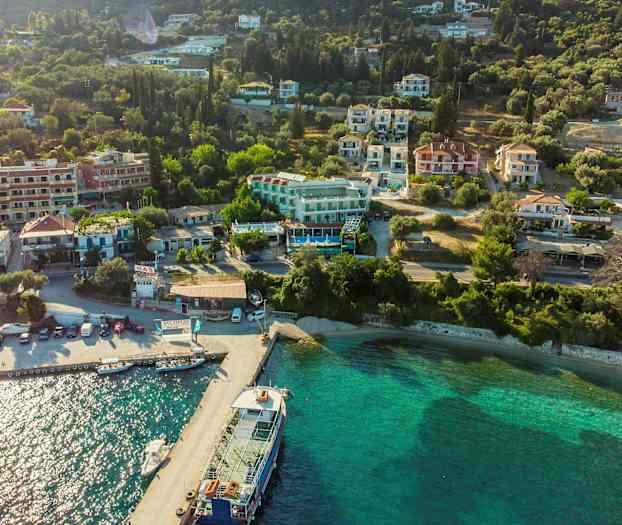 Flygbild över en kuststad med hus och grönområden vid vattnet. (AI-genererad text)