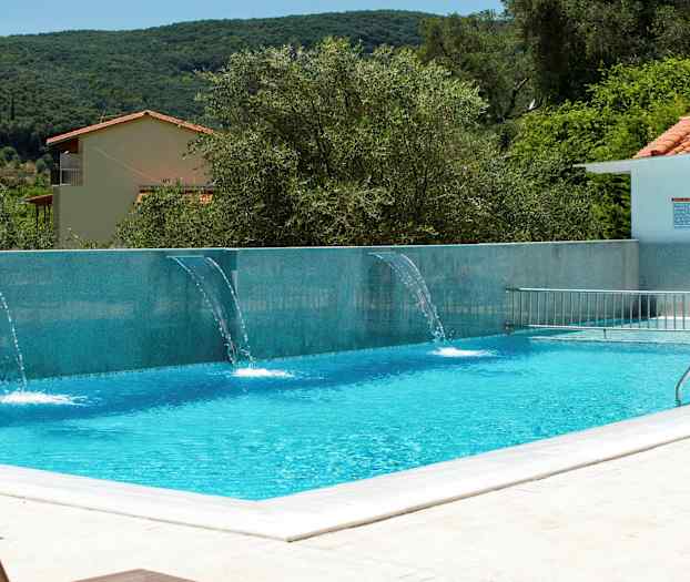 Utomhuspool med vattenstrålar och omgivande grönska. (AI-genererad text)