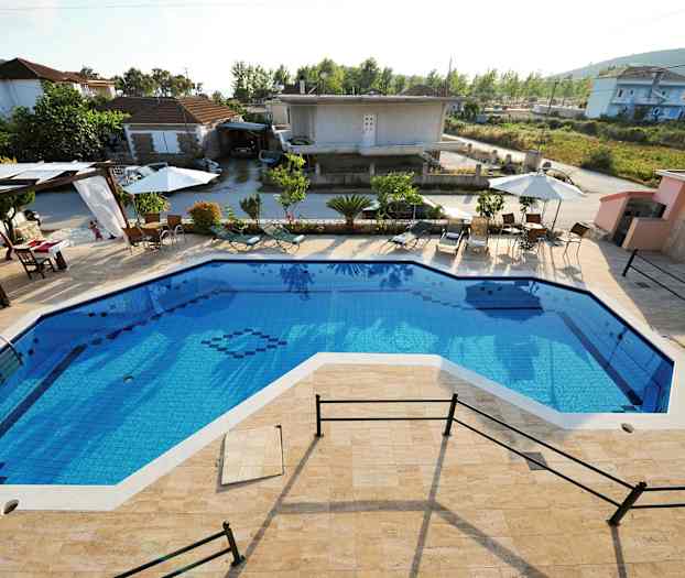 Utomhuspool med omgivande solstolar och parasoller, samt byggnader i bakgrunden. (AI-genererad text)