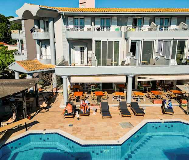 Ett trevåningshotell vid en pool med omgivande solstolar och sittplatser. (AI-genererad text)