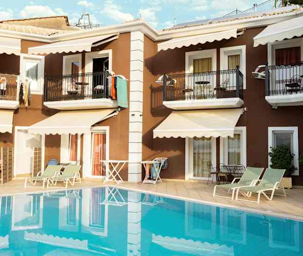 Lägenhetsbyggnad med balkonger och solstolar vid poolen. (AI-genererad text)