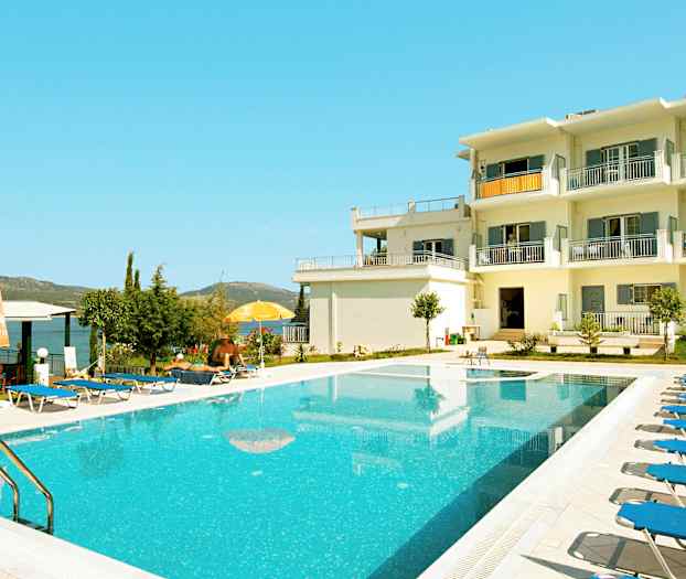 En utomhuspool vid en vit byggnad med balkonger. (AI-genererad text)