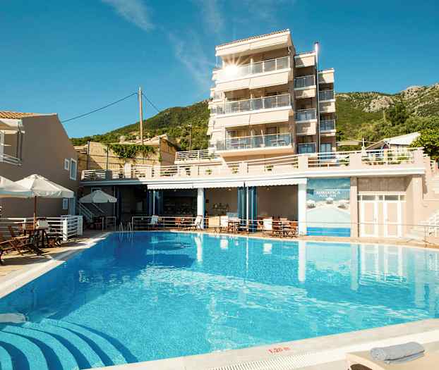 Bild av en byggnad med glasbalkonger, en pool framför och solstolar runt omkring. (AI-genererad text)