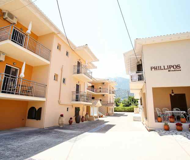 Byggnader med balkonger och genomgående beige fasader samt dekorationer med blommor i krukor. (AI-genererad text)