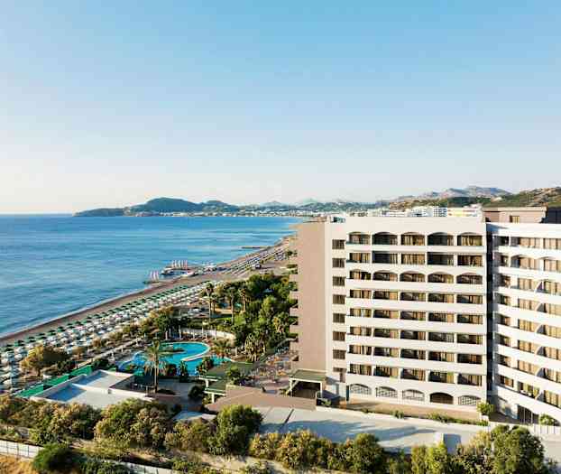 Vy över hotellbyggnad nära sandstrand och hav med solstolar och parasoller. (AI-genererad text)