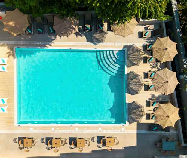 Bild av en utomhuspool omgiven av solstolar med parasoller och bord med stolar. (AI-genererad text)