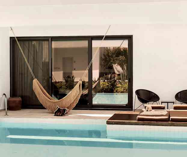Bild av en pool med en hängmatta och solstolar vid kanten. (AI-genererad text)
