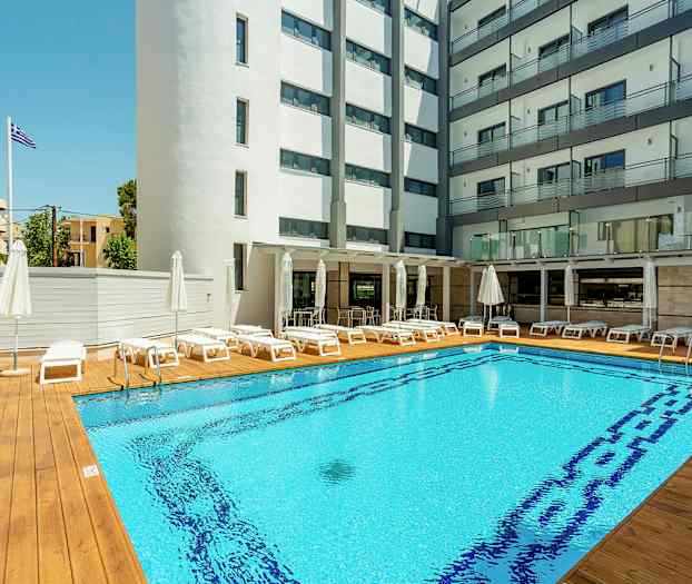 Hotellpool med solstolar och parasoller, omgiven av byggnader. (AI-genererad text)