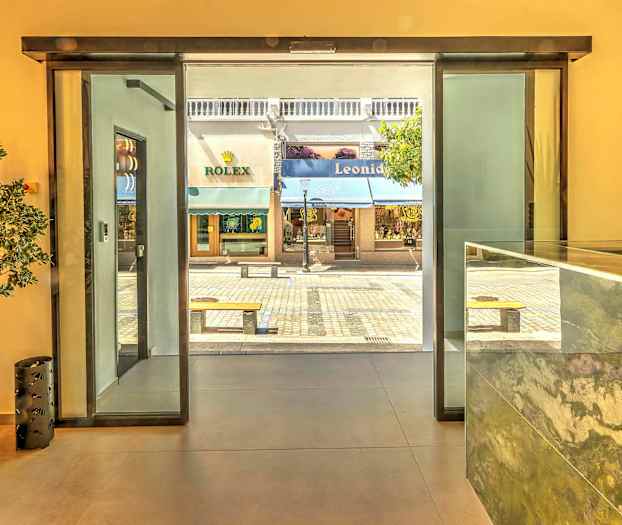 Vy från reception med utsikt mot gågata och butiker genom glasdörr. (AI-genererad text)