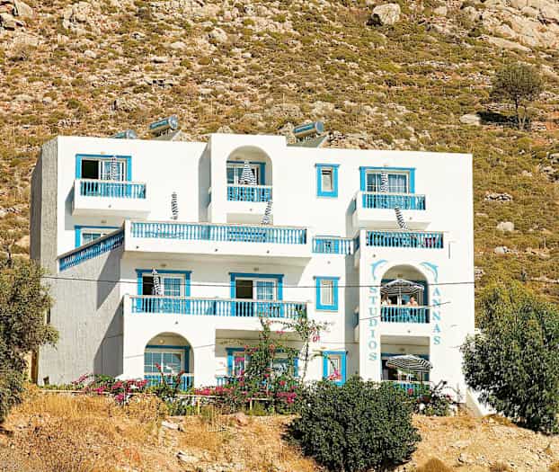 Vit byggnad med blåa detaljer mot en bakgrund av kargt landskap. (AI-genererad text)