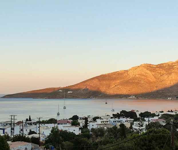 Strandstad med segelbåtar och berg i bakgrunden. (AI-genererad text)