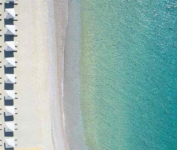 Luftbild av strand med parasoller och klart turkosvatten. (AI-genererad text)