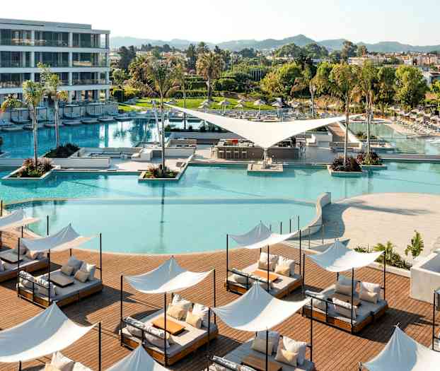 En modern semesterort med swimmingpool, solstolar och grönområden. (AI-genererad text)