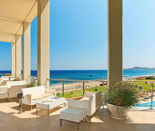 Utsikt över en terrass med sittplatser, mot stranden och havet. (AI-genererad text)