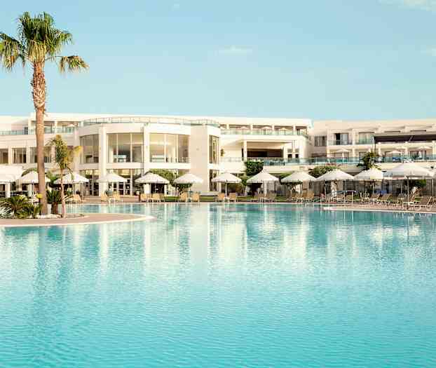 Poolområde vid en modern hotellbyggnad med solsängar och parasoller. (AI-genererad text)