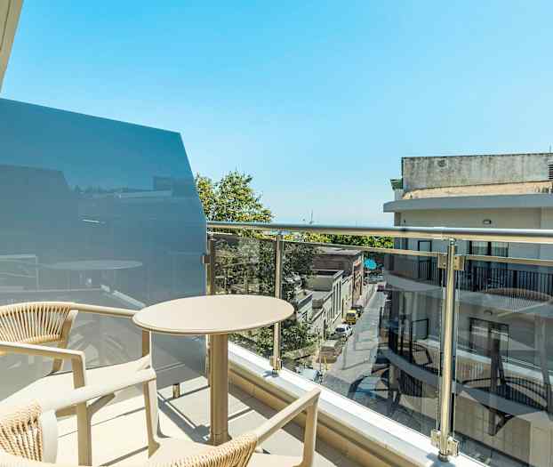 En balkong med bord och stolar i ett stadsmiljö. (AI-genererad text)