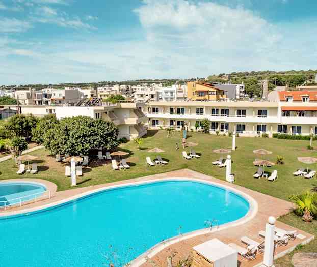 En bild av en pool med solstolar och parasoller på en gräsmatta, omgiven av byggnader. (AI-genererad text)