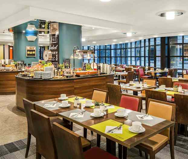 En restauranginteriör med dukade bord och en bufféstation. (AI-genererad text)