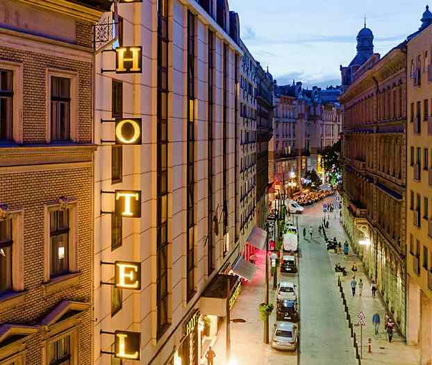 Bild av en stadsgata på kvällen med en hotellskylt på en byggnad. (AI-genererad text)