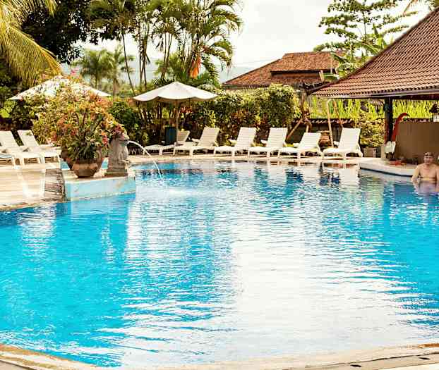 En utomhuspool omgiven av solstolar och parasoller. (AI-genererad text)