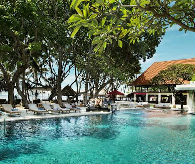 En pool i en trädgård med omgivande solstolar och grönska. (AI-genererad text)