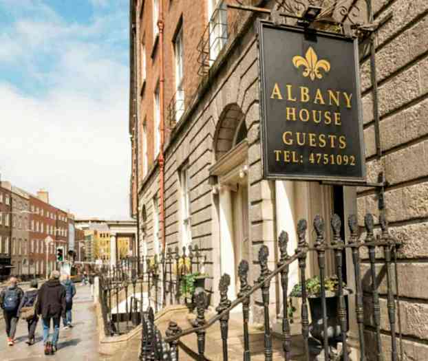 Skylt med texten Albany House Guests vid en husfasad. (AI-genererad text)